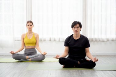 Yoga ve meditasyon yapan genç erkek ve kadın evdeki paspasın üzerinde hayatı dengelemek için meditasyon yapıyorlar. Kadın ve erkek oturma ve egzersiz yoga, sağlık ve spor konsepti..