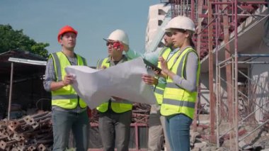 Bir grup müteahhit ve mimar ustabaşıyla birlikte proje planlama projesini işçilere ve proje, inşaat alanı, geliştirme ve yapıya bakmaları için planlama sahasından bahsediyorlar..