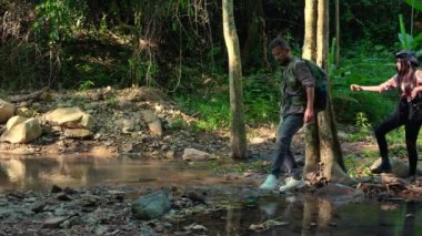 Yetişkin bir erkek ve genç bir kadın ormanda mutlu ve rahat bir şekilde yürüyüş ve sırt çantasıyla geziyor, tatillerde yürüyor ve macera yaşıyor. Haftasonu dinleniyor, meydan okuyor, aktivitelere katılıyor ve yaz aylarında seyahat ediyor..