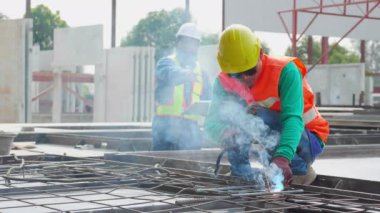 Endüstriyel fabrikayı, kaynakçıyı ya da işçiyi incelerken makineli kaynak demiri kullanan genç Asyalı işçi, yönetici kontrol ederken kaynak makinesi kullanıyor, endüstri kavramı.