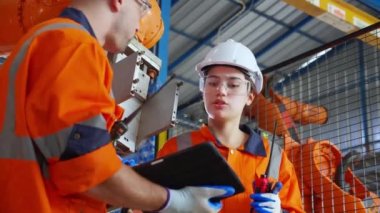 Mühendis erkek ve kadın robot silahlanma teknolojisi hakkında konuşuyor ve tartışıyorlar. Teknoloji zekası ve yenilik. Fabrikada dijital tablet ararken, insanlar makine robotu ile buluşup kontrol ediyorlar..