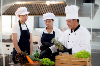 Ekip şefinin talimatı ve çırağı mutfakta birlikte yemek pişirme ve sebze hazırlama, erkek eğitimi ve yemek hazırlama konusunda yardımcı kadın hakkında konuşma..
