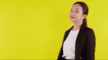 Sarı arka planda tek başına duran takım elbiseli güzel iş kadını portresi, genç Asyalı iş kadını müdür ya da kendine güvenen yönetici gülümsemesi pozitif ve başarılıdır..