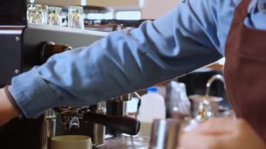 Kahve dükkanındaki sürahide kahve yapmak için buharlı süt ya da köpük hazırlayan baristanın yakın çekim elleri, kapuçino ya da makineli latte yapan Asyalı genç kadın, küçük işletme ya da KME.