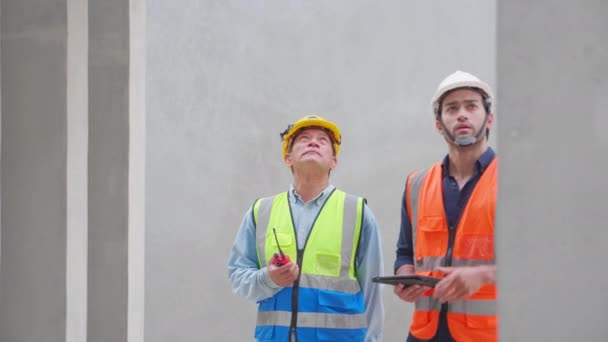 工場内のデジタルタブレットを見ている間 チームの主任と労働者が話して 生産前の壁を検査します セメント壁のマネージャーと労働チェック品質 業界の概念 — ストック動画