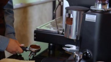 Kafede kahve yapmak için püre yapılırken elinde kahve öğütücü tozu tutan Asyalı genç kadının yakın çekim elleri, kahve makinesi kullanan barista, küçük işletme veya KME.