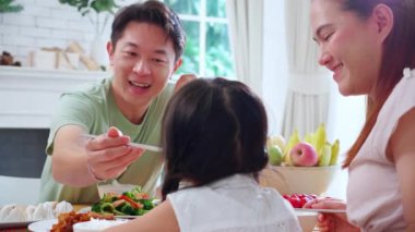 Mutlu Asyalı aile anne, baba ve kız mutfakta birlikte yemek yiyorlar, ebeveyn ve çocuk oturma odasında yemek yiyorlar, bağlanıyorlar ve akrabalar, yaşam tarzları ve beslenme konsepti.