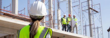 Young caucasian woman engineer command and control labor or coworker while looking blueprint on construction site, architect or contractor control and planning development structure house.