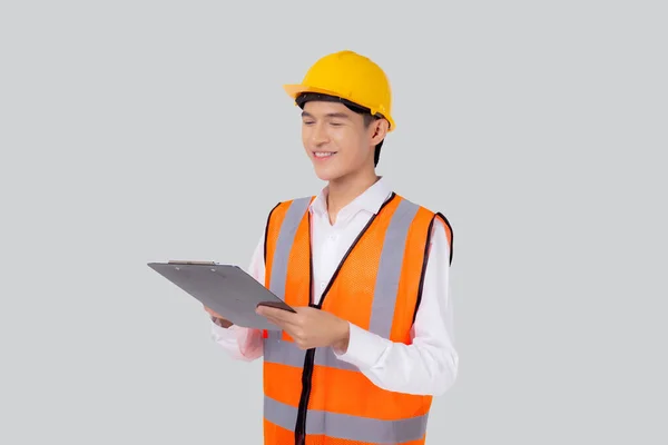 形象年轻的亚洲工程师 头戴头盔或在剪贴板上报告孤立的白色背景 建筑师或承包商为规划 工业概念进行检查和诊断 — 图库照片