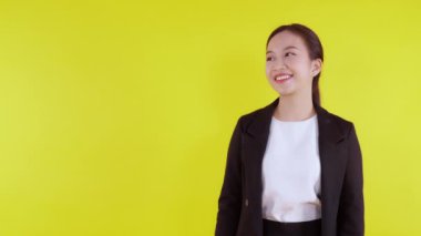 Sarı arka planda izole edilmiş genç Asyalı iş kadını portresi, reklamcılık ve pazarlama, kadın sürprizi ve heyecanı, iş kadını kendine güvenen ifade ile başparmak işareti.