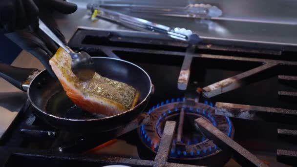 レストラン 栄養と健康 料理とレシピ 肉と食品 料理とライフスタイルの概念でキッチンで鍋にマリネ若いアジアのシェフの男揚げサーモンフィッシュステーキのクローズアップ手 — ストック動画