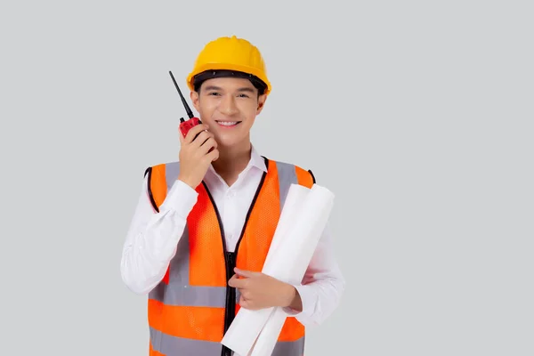 労働者の隔離された白い背景と話すコマンドのためのラジオを使用してヘルメットを身に着けている肖像若いアジアのエンジニアの男性は ハンサムな男性は設計図を保持する建築家や請負業者 産業概念 — ストック写真