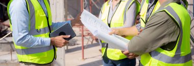 Bir grup müteahhit ve mimar ustabaşıyla birlikte proje planlama projesini işçilere ve proje, inşaat alanı, geliştirme ve yapıya bakmaları için planlama sahasından bahsediyorlar..