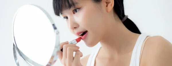 美丽的年轻亚洲女人在嘴唇上涂上红色口红 漂亮的女孩在镜子前看着镜子 用优雅的唇彩化妆 构成了女性的性感 护肤和健康的概念 — 图库照片