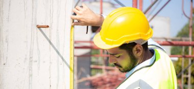 Engineer young man using tape measure for check and examining length of structure with professional at construction site, architect inspection and improvement infrastructure, industry concept.