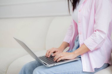 Closeup hands business woman work from home with laptop computer online to internet on sofa in living room, freelance girl using notebook sitting on couch with comfort and relax, lifestyles concept.