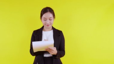 Asyalı genç iş kadını portresi sarı arka planda izole edilmiş bir not, ajan iş kadını veya sekreter planlama ve imza belgesi, pazarlama ve finansal konsept.