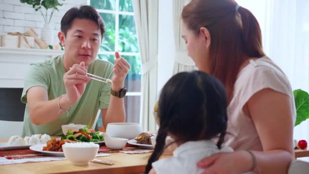 幸せアジアの家族の母親と父親と娘は 家庭で一緒に台所で食べ物を食べる リビングルームで食事に座って親と子供 結合と関係 ライフスタイルと栄養の概念 — ストック動画