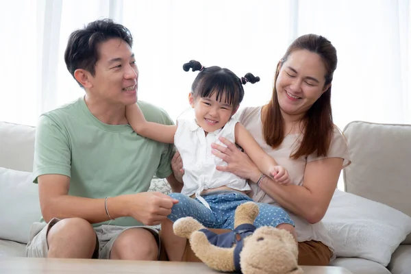 stock image Happiness asian family father and mother and daughter sitting on sofa in living room at home, happy dad and mom and kid sitting and relax with comfortable on couch together, lifestyles concept.