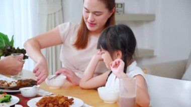 Mutlu Asyalı aile anne, baba ve kız mutfakta birlikte yemek yiyorlar, ebeveyn ve çocuk oturma odasında yemek yiyorlar, bağlanıyorlar ve akrabalar, yaşam tarzları ve beslenme konsepti.