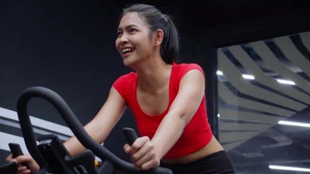 年轻的亚洲女子骑自行车机参加健身俱乐部的健身训练 骑自行车参加运动 并为健康和减肥 运动和保健而积极集中精神 — 图库视频影像