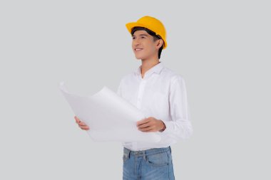 Portrait young asian man is engineer wearing helmet holding and looking blueprint with confident isolated on white background, handsome male is architect or contractor, worker or labor concept.