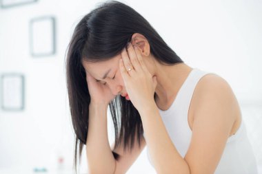 Genç Asyalı kadın yatak odasında yatak odasında baş ağrısı, mutsuz kadın yorgunluğu ve baş ağrısı, endişe ve rahatsızlık, baş dönmesi ve düzensizlik, tıbbi ve sağlık konsepti.