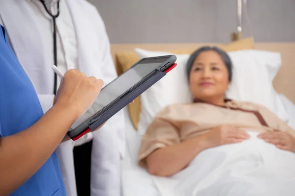 간호사는 관리에 태블릿으로 병원내 의노인 환자와 병세를 진단하고 설명하고 — 스톡 사진