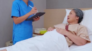 Hemşire dijital tablete tıbbi ve sağlık hizmetleri hakkında rapor ya da reçete yazarken, hastanede hasta olan yaşlı hastaya, tıbbi konsepte açıklama ve kontrol yapıyor ve kontrol ediyor..