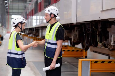 Kafkasyalı genç mühendis ve kadın, istasyon, ulaşım ve araçta başarı için anlaşmalı olarak bakım ve el sıkışma planlamak ve anlaşmak üzere planlama ve elektrikli treni kontrol etmek için plan toplantıları düzenliyor..