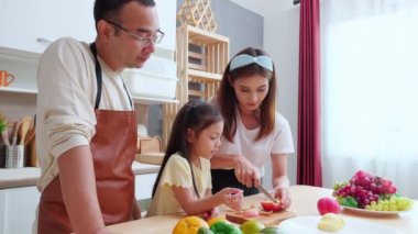 Mutfakta baba, anne ve kızıyla mutlu bir aile. Bu arada anne evde elmalı meyve doğruyor. Anne, baba ve çocuk birbirine bağlanıyor, yaşam tarzları ve beslenme kavramları var..