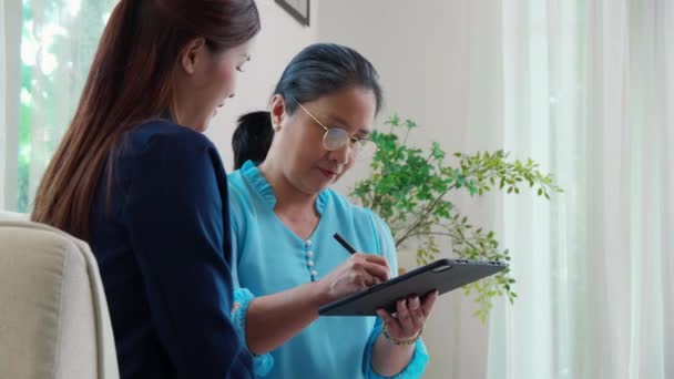エージェント保険の生命または健康またはアドバイザー若いアジアの女性と高齢女性は リビングルームのデジタルタブレットで合意と署名を行い ビジネス 保険のコンセプトを計画 — ストック動画