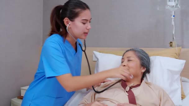 病院病棟 看護師診断患者 健康コンセプトで心拍を聞くためのステススコープを有する患者高齢者による専門医女性検診 — ストック動画