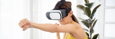 Oturma odasında birlikte egzersiz yaparken vr kulaklık takan genç beyaz kadın, sanal gerçekliğin yenilikçi ve fütüristik versiyonu, kadın oyun oynuyor ve eğleniyor.