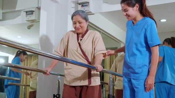 Młody Fizjoterapeuta Pomaga Starszemu Pacjentowi Podczas Terapii Poradniczej Chodzeniem Pokoju — Wideo stockowe