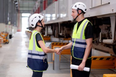 Kafkasyalı genç mühendis ve kadın, istasyon, ulaşım ve araçta başarı için anlaşmalı olarak bakım ve el sıkışma planlamak ve anlaşmak üzere planlama ve elektrikli treni kontrol etmek için plan toplantıları düzenliyor..