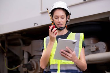 Kafkasyalı genç bir mühendis, radyo komutası altında çalışan bir işçiyle birlikte istasyonda elektronik trenin bakımını kontrol ediyor ve dijital tablete bakıyor, ulaşım ve altyapıyı kontrol ediyor..