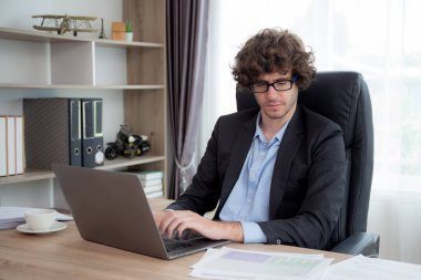 Kafkasyalı genç işadamı pazarlama için dizüstü bilgisayar planlaması kullanıyor, iş adamı not defterine yazı yazıyor ve grafiğe bakıyor, yönetici ya da yönetici ve yatırım, iş konsepti.