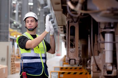 Genç beyaz mühendis ya da işçi istasyon, ulaşım ve altyapı, müfettiş ya da teknisyen kontrolleri ve onarımı için elektrikli trenin bakımını araştırıyor ve kontrol ediyor..