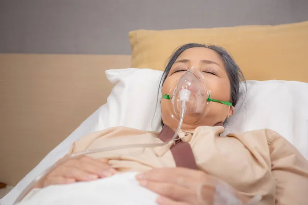 Patient elderly asleep with disease or unconscious in oxygen mask on bed at hospital ward, senior sick urgency in emergency room, respiration and lung, health and medicine, insurance and medical.