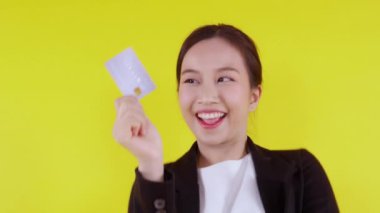 Güzel Asyalı genç iş kadınının portresi kredi kartı ya da alışveriş için kredi kartı ya da banka kartı taşıyor ve mali açıdan izole edilmiş sarı bir geçmişi var. ATM, finans konsepti gösteren bir iş kadını.