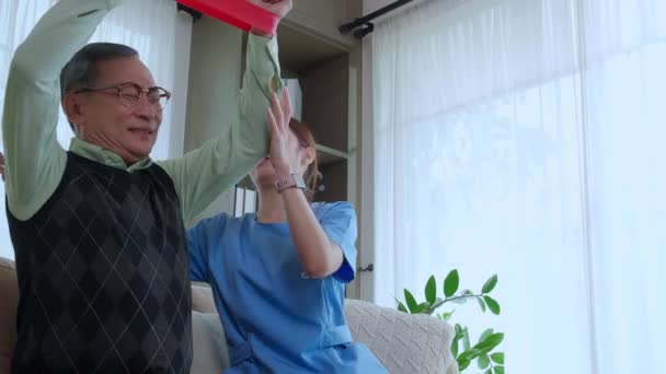 亚洲的护理者妇女或护士训练老年人伸展手臂进行锻炼 同时在家中客厅 护理者或理疗师的治疗和康复中心帮助老年人用手锻炼 — 图库视频影像