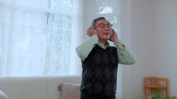 Pria Senior Asia Yang Mengenakan Headphone Mendengarkan Musik Dengan Smartphone — Stok Video