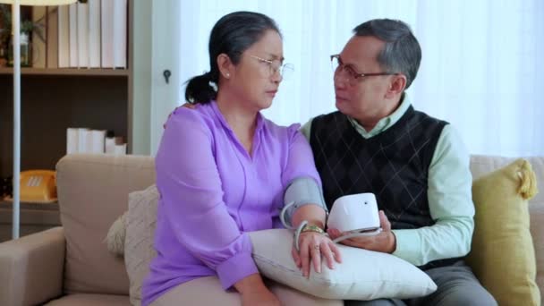 Asian Senior Couple Sitting Sofa Checking Blood Pressure Pressure Gauge — Stock Video