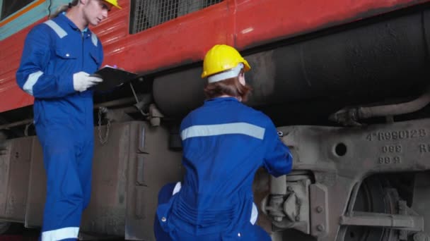 年轻的高加索工程师男女维修和修理站内的火车柴油机 小组工程师检查系统运输 技术人员检查基础设施 运输和工业 — 图库视频影像