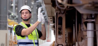 Genç beyaz mühendis ya da işçi istasyon, ulaşım ve altyapı, müfettiş ya da teknisyen kontrolleri ve onarımı için elektrikli trenin bakımını araştırıyor ve kontrol ediyor..