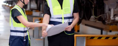 Kafkasyalı genç mühendis ve kadın ya da işçi istasyon, ulaştırma ve altyapı, müfettiş ya da teknisyen kontrolleri için planlı ve elektrikli trenin bakımını kontrol ediyor..