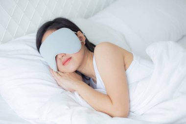 Güzel Asyalı genç bir kadın örtülü göz takıyor ve yatak odasında başı yastıkta uyuyor rahatlık ve mutlulukla, rahatlık ve rahatlık için boş vakti olan bir kız, yaşam tarzı konsepti..
