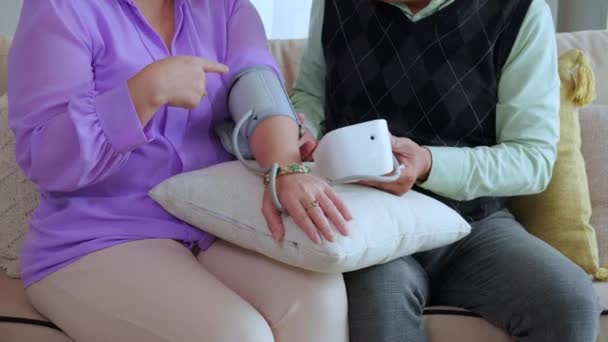 Asiático Casal Sênior Sentado Sofá Verificando Pressão Arterial Com Medidor — Vídeo de Stock