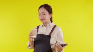 Sarı arka planda önlük giyen Asyalı genç baristanın portresi. Garson ya da girişimci heyecanlı, küçük işletme ya da girişimci garson garson garson..